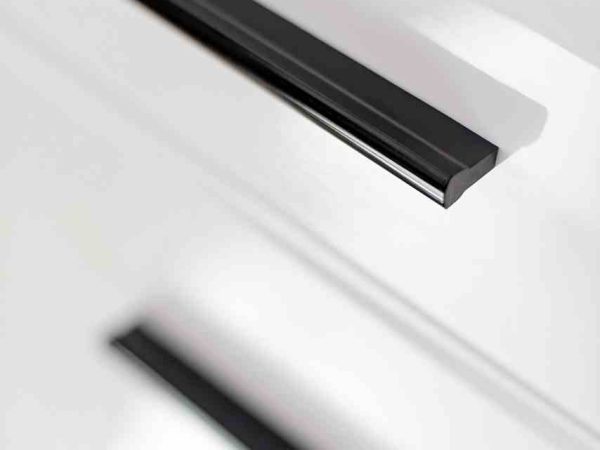 Detal czarnego uchwytu na białym froncie z połyskiem i podświetleniem