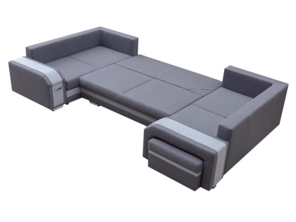 Szary narożnik w jasnym salonie z dużym oknem i czarnym stołem