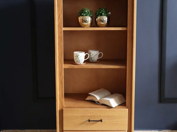 Witryna z naturalnego drewna, otwarte półki i szuflady, tło granatowej ściany