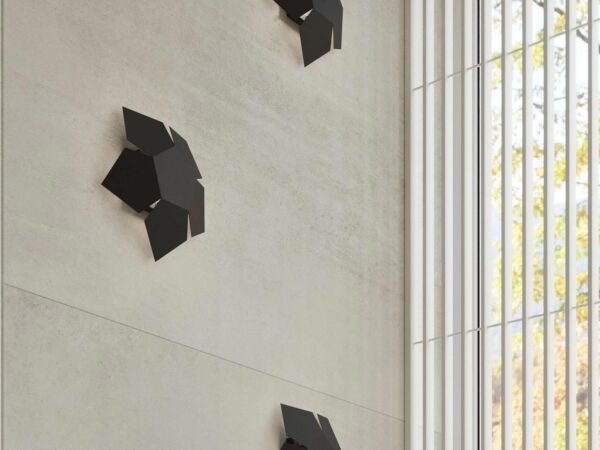 Trzy czarne lampy na ścianie – wystrój sypialni z betonu