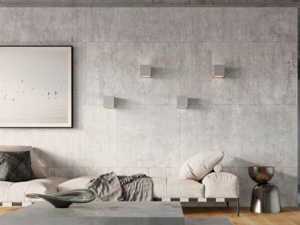 Betonowe kinkiety w minimalistycznym salonie z szarą sofą