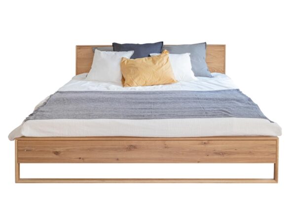 Drewniane łóżko z białą pościelą – styl nowoczesny z minimalistycznym designem