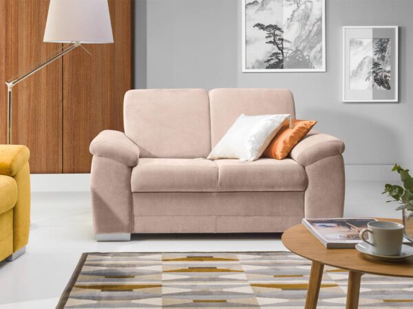 Mała sofa tapicerowana w kolorze różowym z ozdobną poduszką