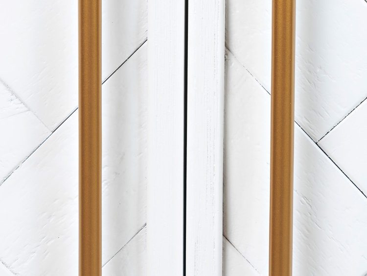 Detal złotych uchwytów w białej komodzie z frezowanym frontem