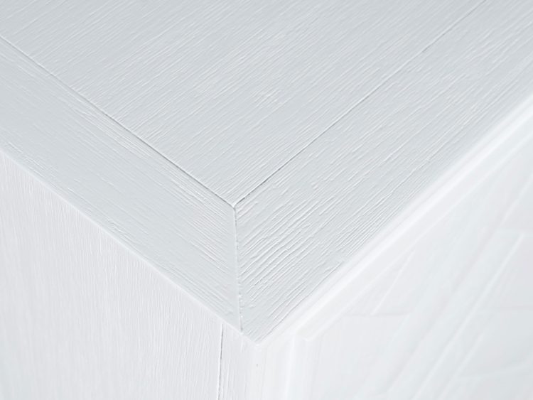 Detal blatu białej komody z frezowanym wykończeniem w stylu glamour