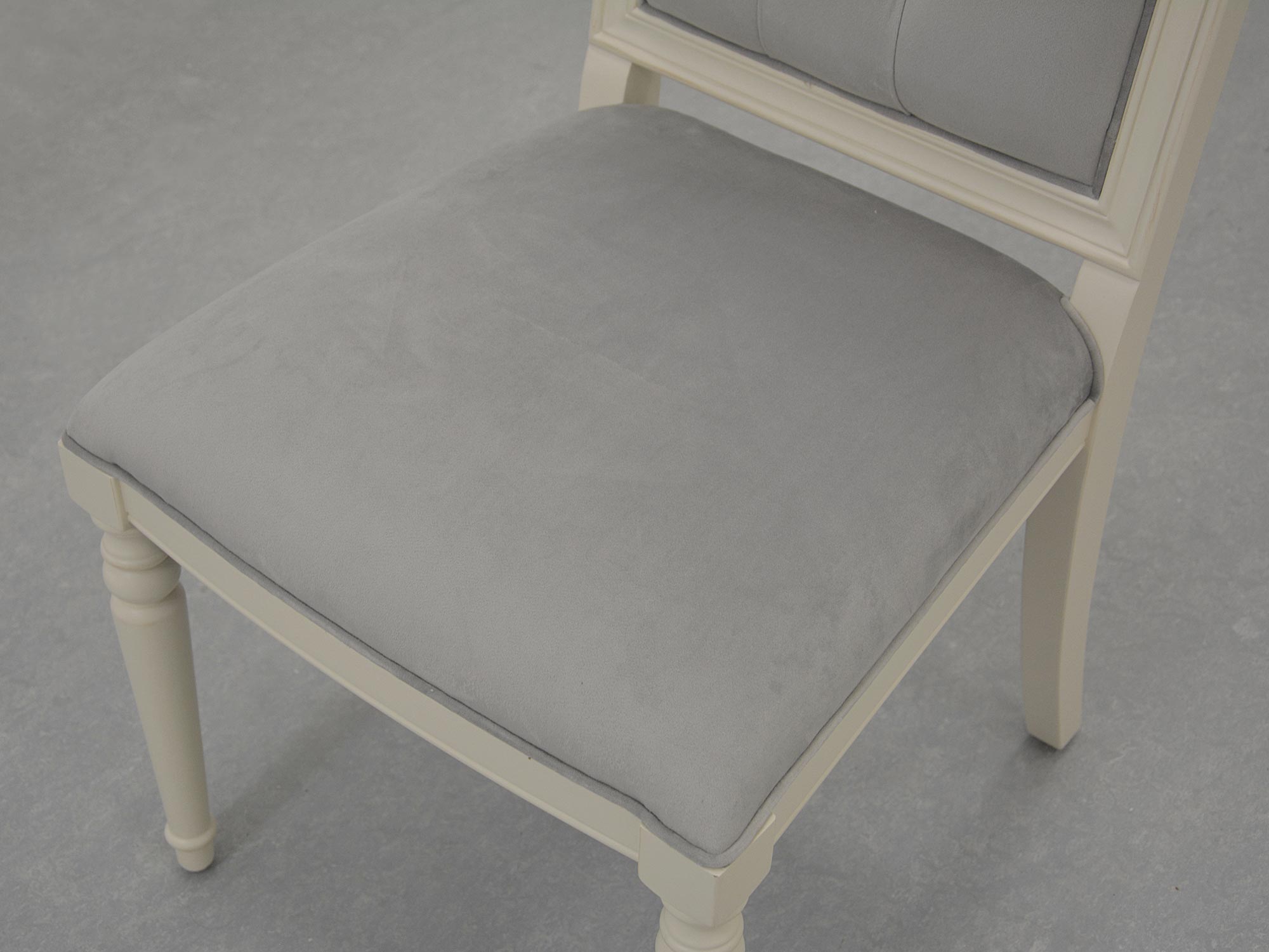 Zbliżenie na siedzisko krzesła z jasnoszarą tapicerką welurową