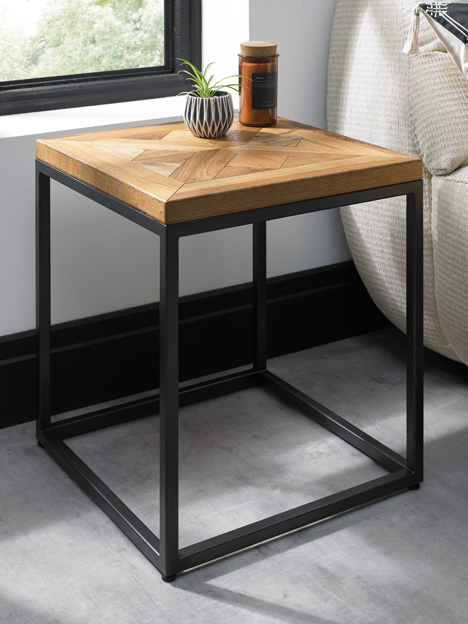 Kwadratowy stolik pomocniczy z blatem w jodełkę i czarną metalową ramą, widok z boku