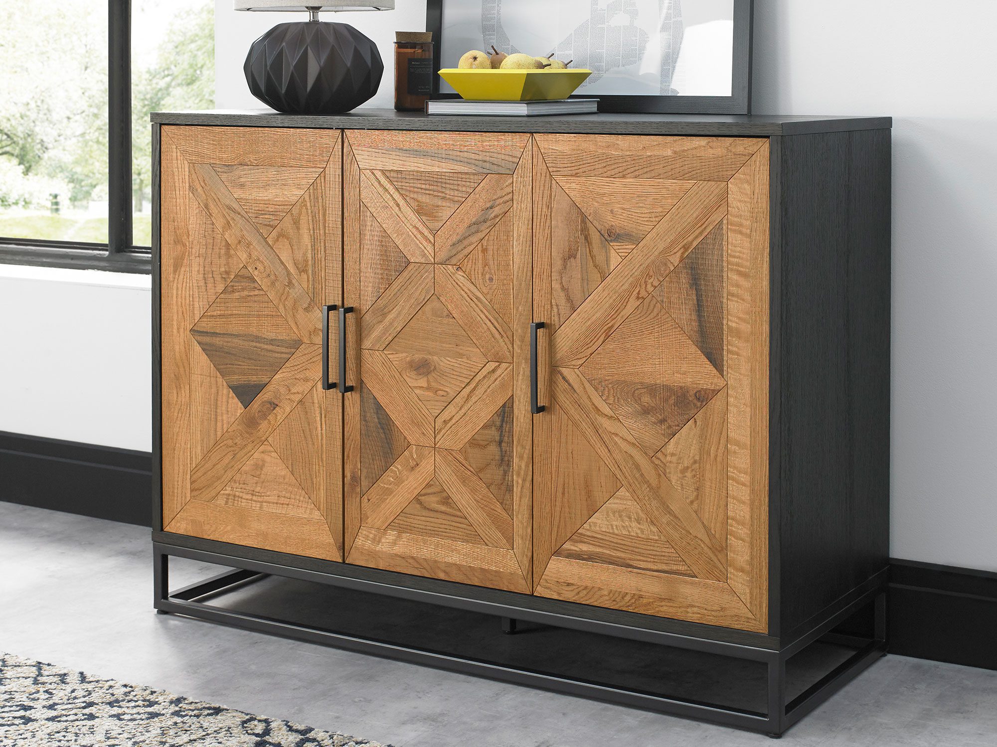Komoda z frontem w jodełkę i czarnym uchwytem, zbliżenie na drzwi