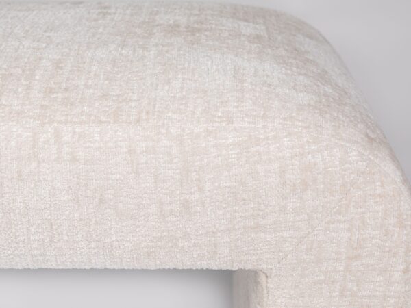 Detal narożnika łóżka w kremowej tkaninie boucle