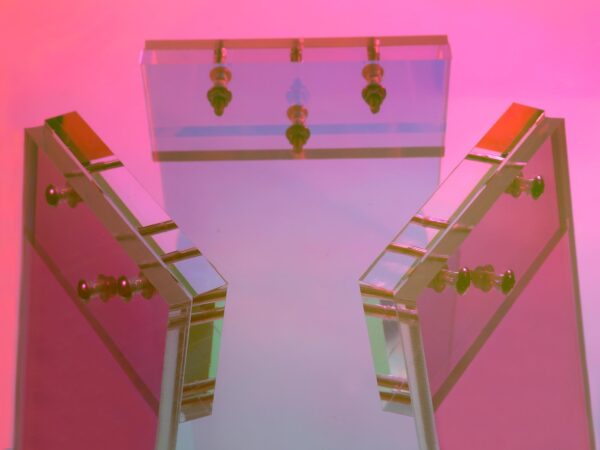 Designerski stolik z barwionymi nogami w odcieniach fuksji i turkusu oraz szklanym blatem