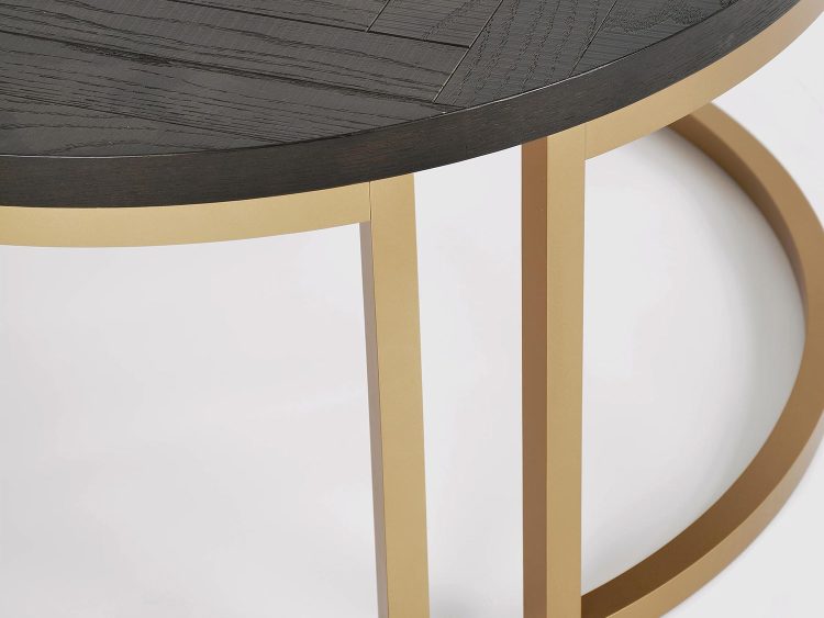 Zbliżenie na stolik kawowy okrągły czarny z blatem w jodełkę i złotą ramą