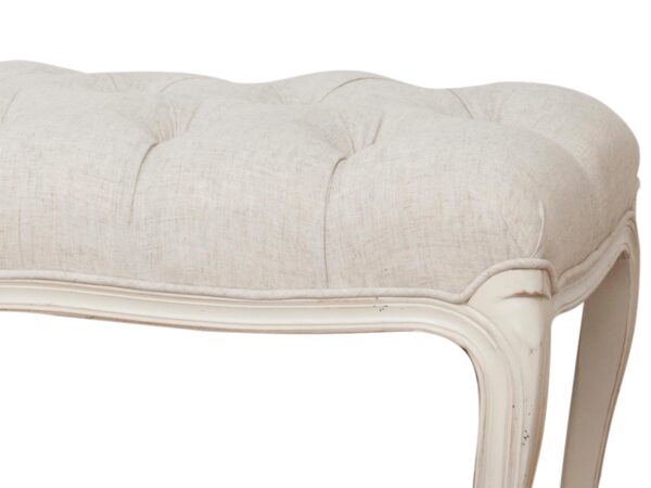 Zbliżenie na siedzisko pikowanej ławki z rzeźbionym rantem