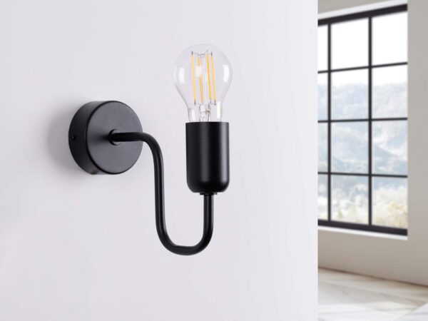 Czarny kinkiet industrialny zamontowany na białej ścianie